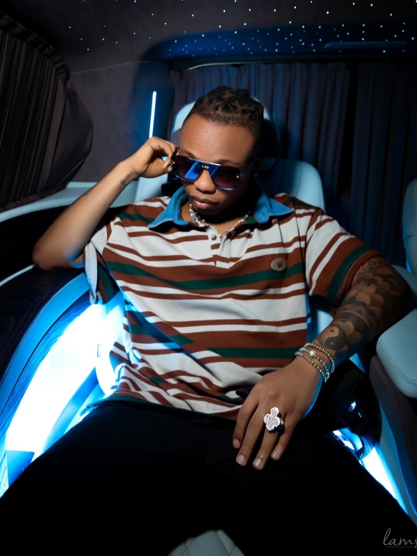A Man In A Striped Polo Shirt And Sunglasses Sitting In A Car With Blue Interior Accent Lighting.